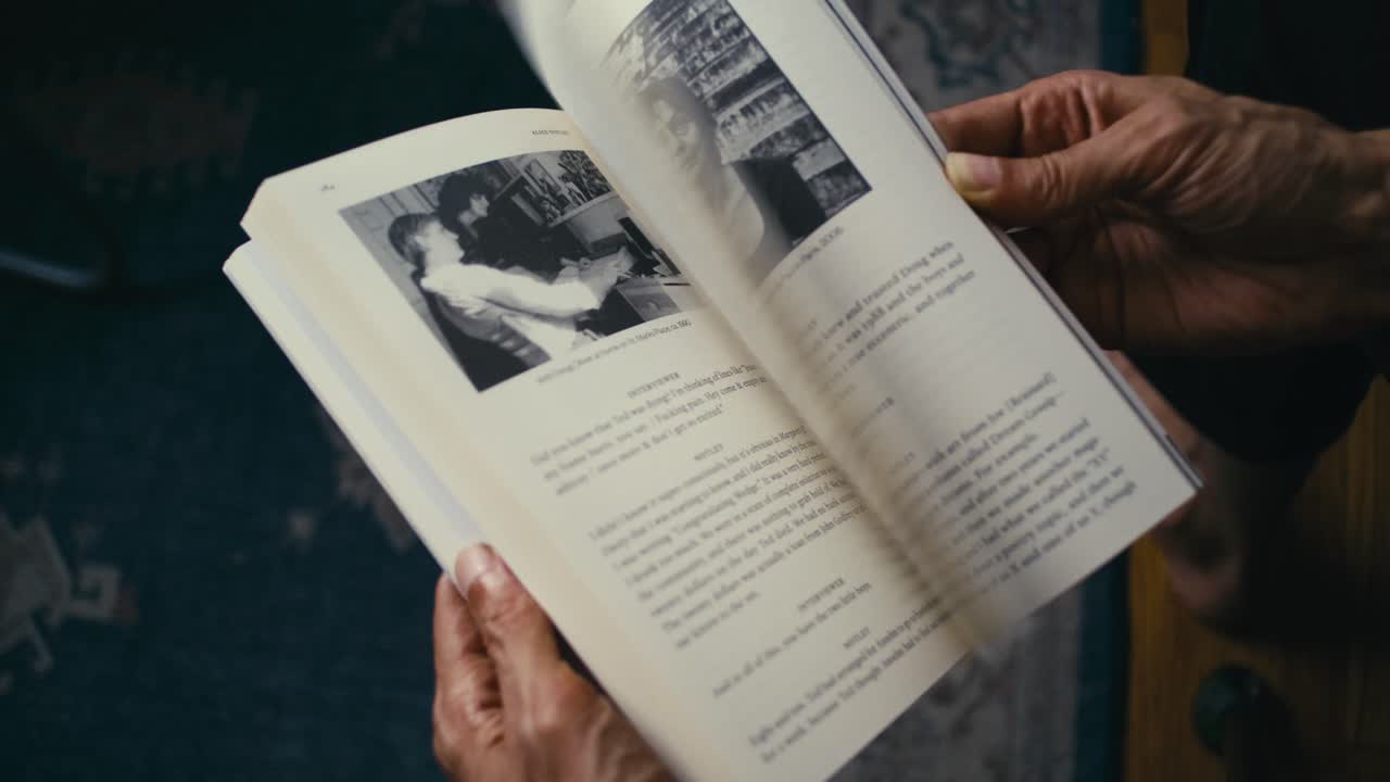 Close-up of man flipping through the pages of an open book indoors. Soft natural lighting. Perfect for themes of reading, learning, literature, studying, research, relaxation, or knowledge