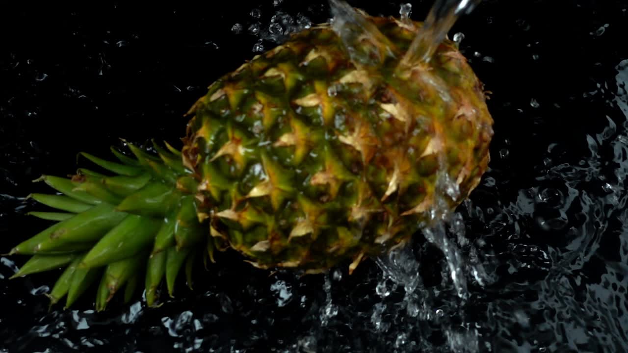 The stream of water flows on pineapple. Slow motion