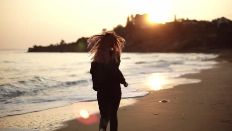 A-woman-runs-along-the-beach-from-behind,-seashore-evening-of-autumn