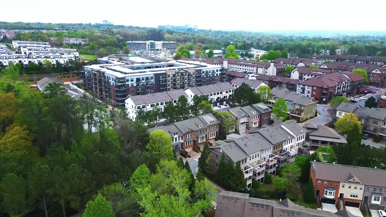 Multi-family units and townhouses in american suburb during sunny day with green trees. Aerial backwards wide shot. Atlanta City, Georgia in spring season.