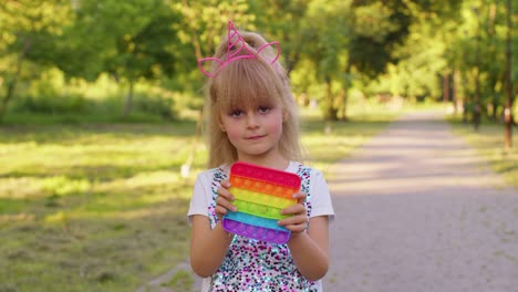 Child-girl-kid-playing-squeezing-anti-stress-pop-it-touch-screen-toys-simple-dimple-game-in-park