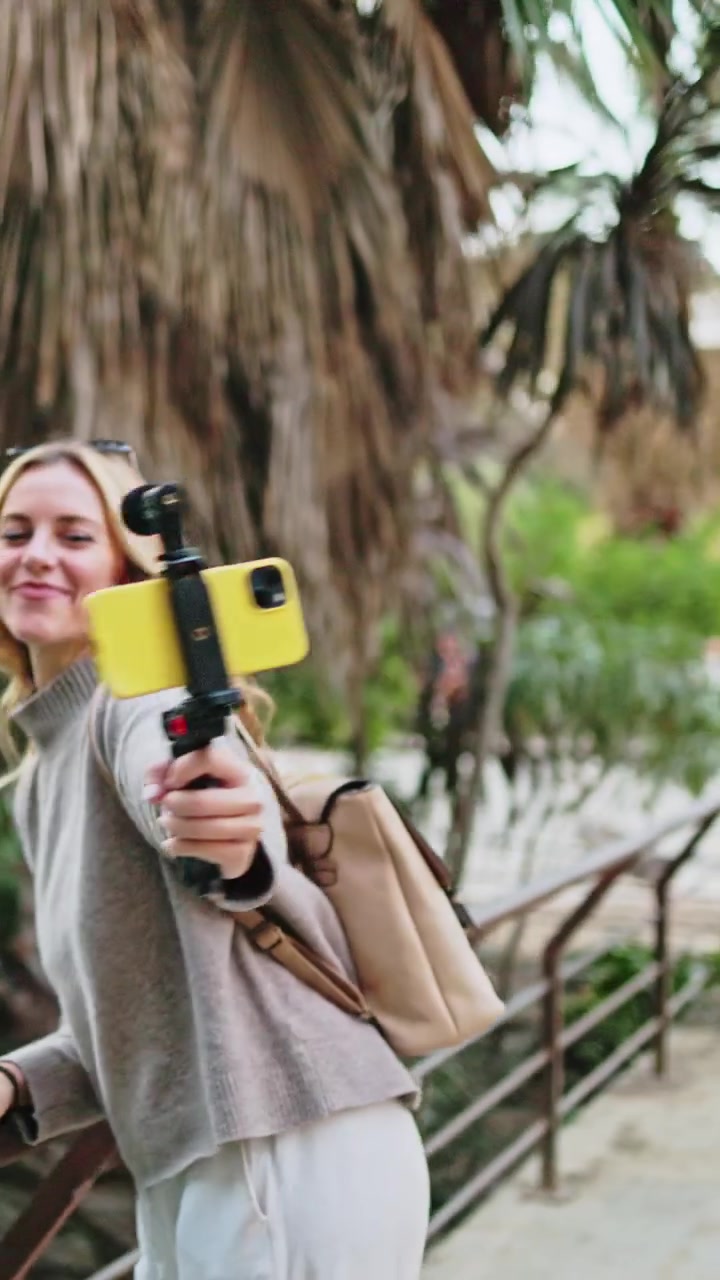 Giovane donna felice che vlogga con smartphone e gimbal al parco