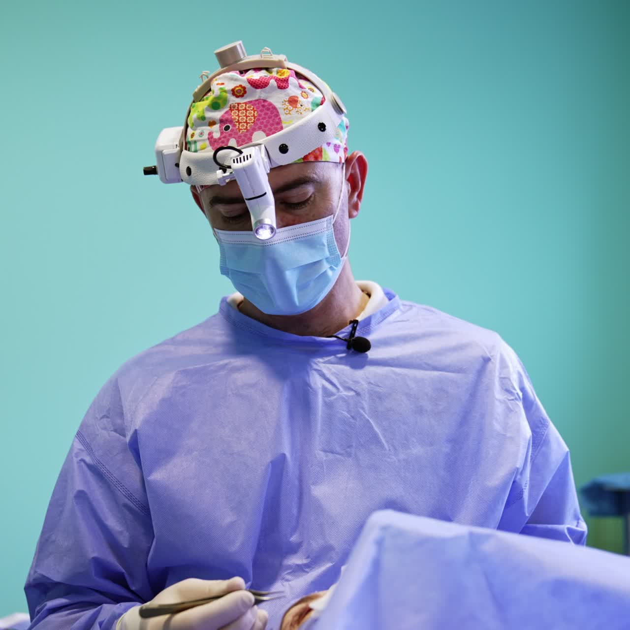 Doctor in mask and headlight speaks on the performed surgery. Surgeon explains the work done