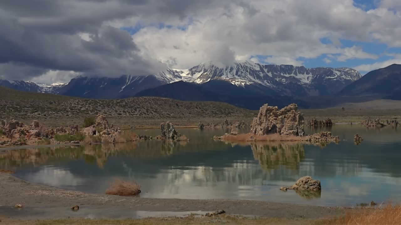 Tufi del Mono Lake che emergono dall'acqua, riflettendo le montagne della Sierra Nevada e il cielo in California, USA