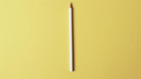 overhead view of white crayon with copy space on yellow background, in slow motion