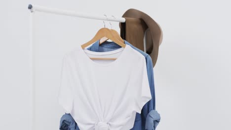 Video-of-white-and-denim-t-shirt-on-hangers,-hat-and-copy-space-on-white-background