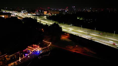 tráfico nocturno en la ciudad de katowice, tres libras ubicación - carreteras iluminadas y bar a la orilla del lago - vista aérea 4k