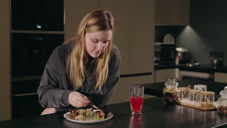 woman eating sushi in kitchen