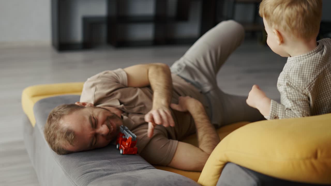 padre feliz jugando con el niño en el sofá en casa
