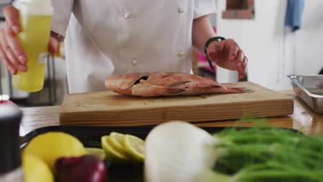 cocinera caucásica preparando un plato y sonriendo en una cocina