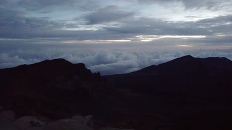 Stunning-Timelapse-of-a-dawn-with-the-sun,-crater-and-puffy-cloud-cover-at-the-top-of-volcano-summit-crater-at-Haleakala-National-Park-which-is-a-massive-shield-volcano,Maui,Hawaii,USA