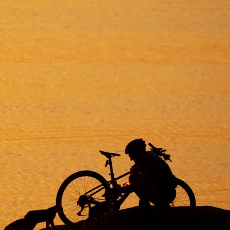 man with bicycle resting near river