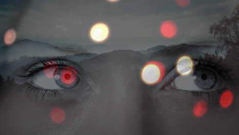 glowing spots of light over close up of female eyes against landscape with mountains