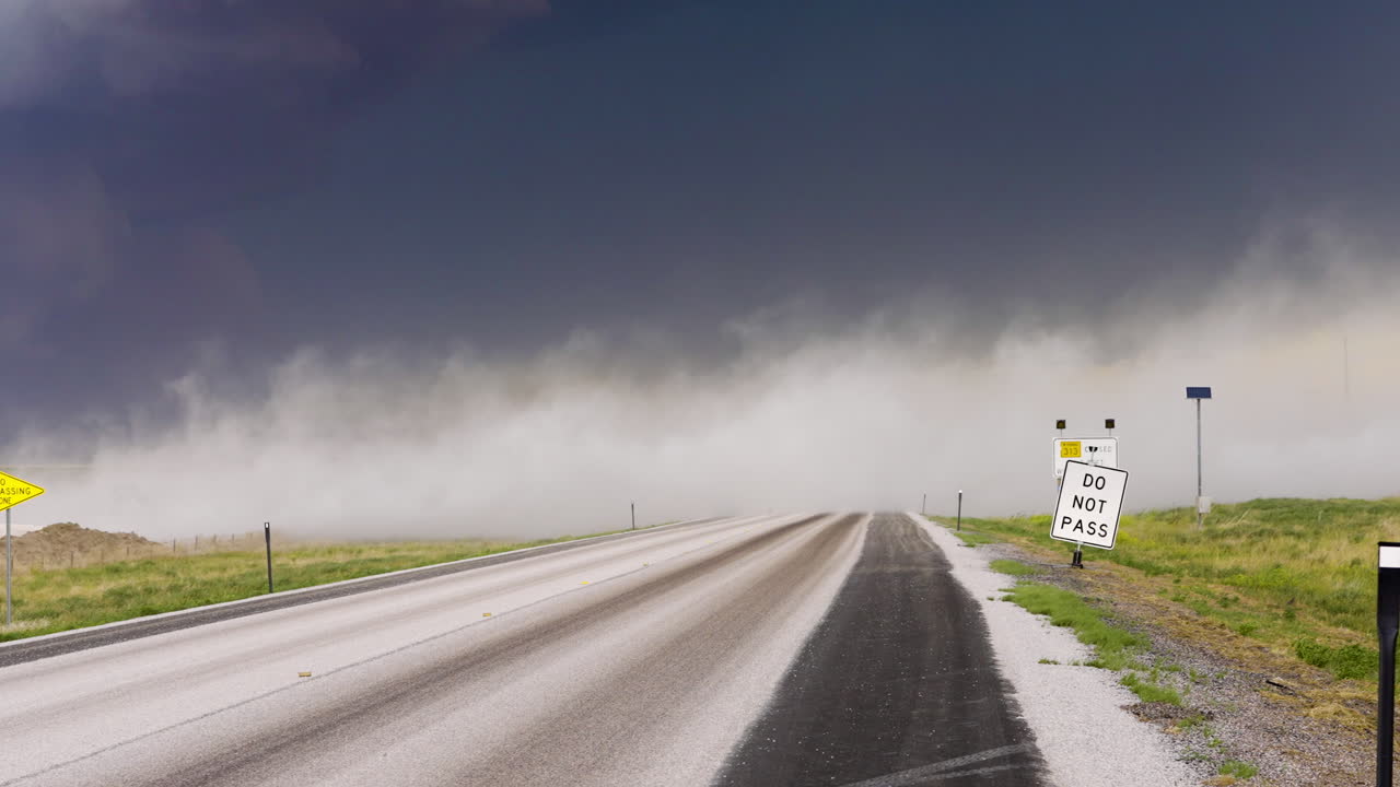 Dust clouds quickly blow across a road in stormy conditions
