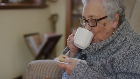 Porträt-Einer-älteren-Frau,-Die-Tee-Trinkt-Und-Einen-Entspannten-Ruhestandslebensstil-Genießt,-Lächelnd,-Glücklich,-Komfortabel,-Senior-Rentnerin-Im-Friedlichen-Wohnzimmer-Zu-Hause