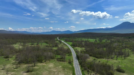 Aerial-shot-of-a-road-that-stretches-across-a-mountain-plateau-overgrown-with-grass-and-groves