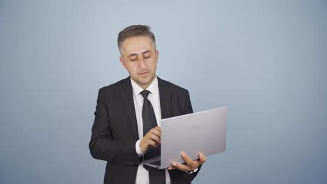 hombre de negocios mirando la computadora portátil con expresión cansada.