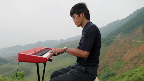 elegant southeast asian man playing piano in hilltop jungle