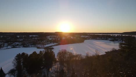 Luftaufnahme-Eines-Wintersonnenuntergangs-In-Richtung-Sonne-Und-Stadt