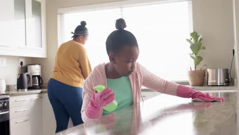 Glückliche-Afroamerikanische-Mutter-Und-Tochter-Putzen-Arbeitsplatte-In-Der-Küche,-Zeitlupe