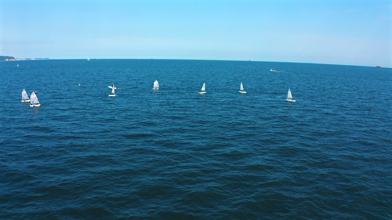 Aerial view of Optimist dinghy boats sailing on the blue ocean at sunny day