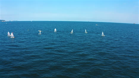 aerial view of optimist dinghy boats sailing on the blue ocean at sunny day