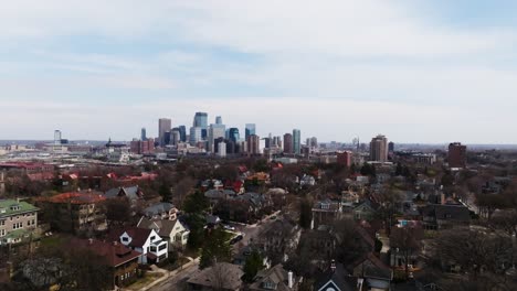 orbiting drone shot of the minneapolis skyline on a partly cloudy day with the city suburbs in the foreground