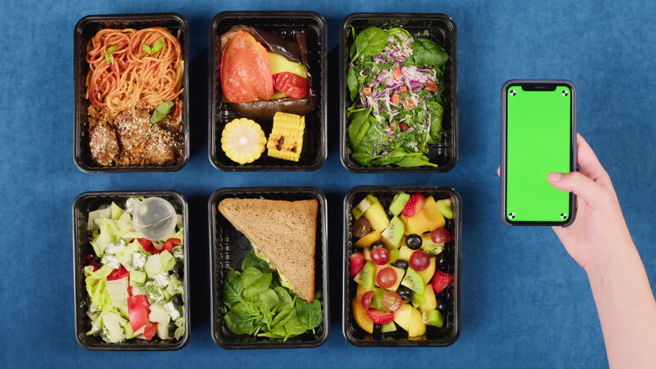 Variety of Healthy Meal Prep Boxes and Hand Holding Green Screen Phone