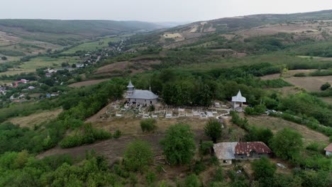 toma en órbita de una iglesia distintiva en la cima de una colina verde, montañas en el fondo, rumania