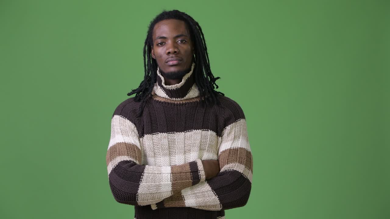 Giovane e affascinante uomo africano con i dreadlock su sfondo verde