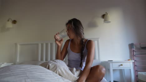 mujer bebiendo agua en la cama