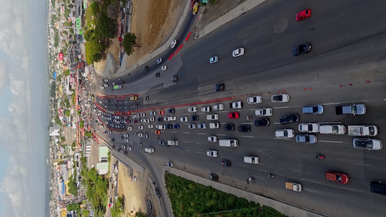 Car traffic along Kilometer 9 of Duarte highway, Santo Domingo city, Dominican Republic. Aerial forward and vertical format
