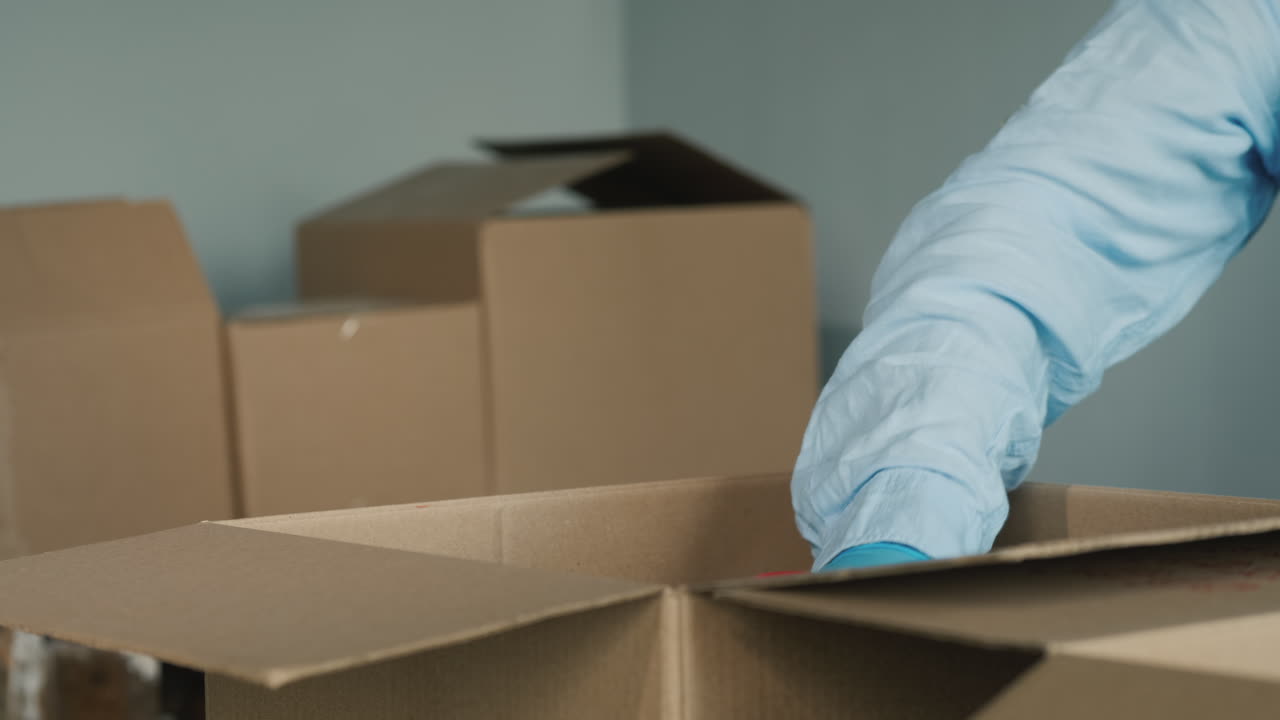 voluntario prepara kits de comida empacando productos enlatados en una caja de cartón