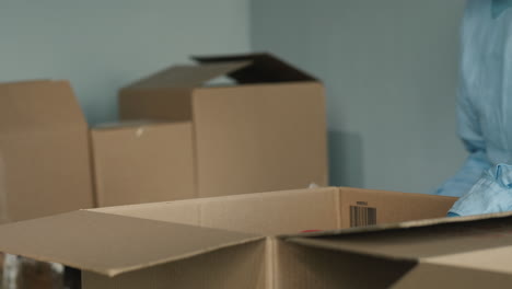 voluntario prepara kits de comida empacando productos enlatados en una caja de cartón