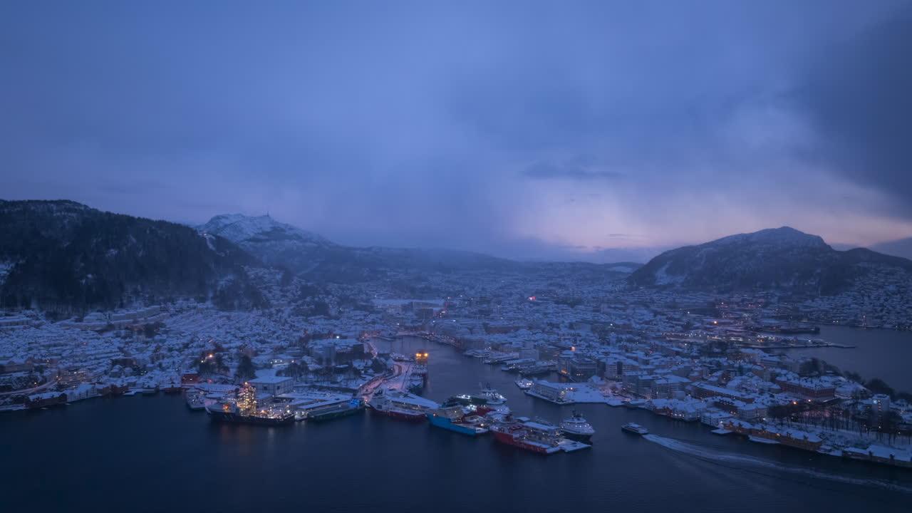 Aerial hyperlapse of beautiful Bergen in winter just after sunset with snow showers passing by