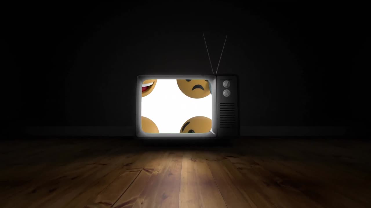 Molteplici emoji con faccina sullo schermo di una televisione su una superficie di legno su sfondo nero