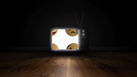 Multiple-face-emojis-on-television-screen-over-wooden-surface-against-black-background