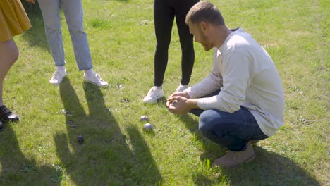 side view of a caucasian young man calculating distance between petanque balls in the park