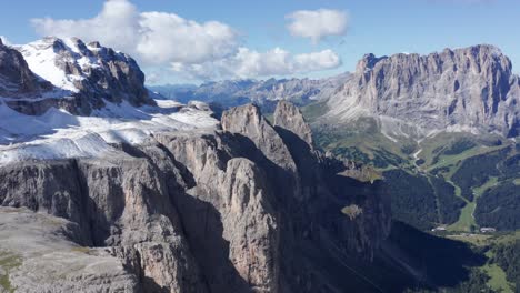 Aerial-panoramic-shot-of-Sella-Group-with-Sassolungo-range-on-a-sunny-day-with-clouds-and-snow-in-Italy,-Dolomites