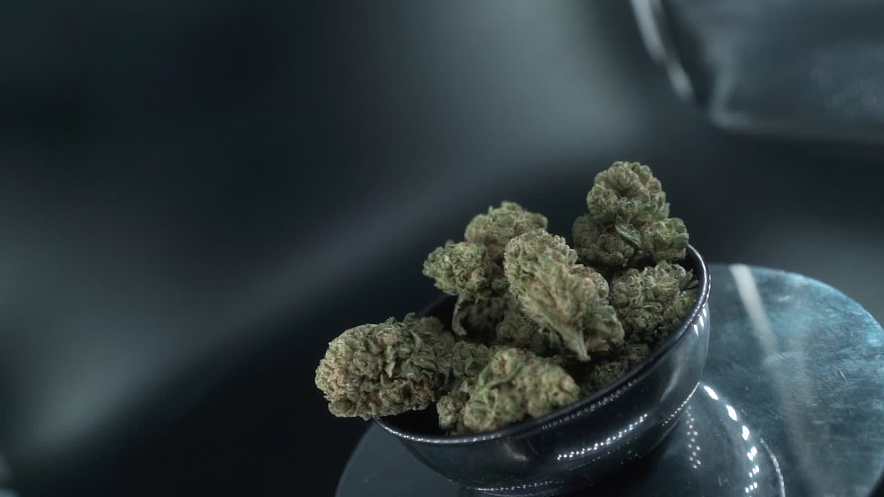 brotes de marihuana secos verdes disparado de cerca, montón de plantas de marihuana secas en un cuenco brillante, cepas de tricomas, en un soporte giratorio reflectante, luces de estudio, cinematográfico suave girar movimiento lento 120 fps