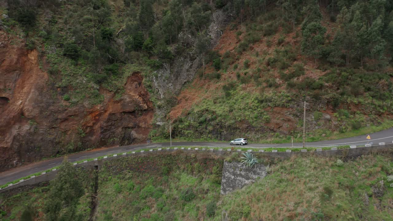 무성한 녹색 마데이라의 산길을 통해 내리막길을 운전하는 자동차, 측면 보기