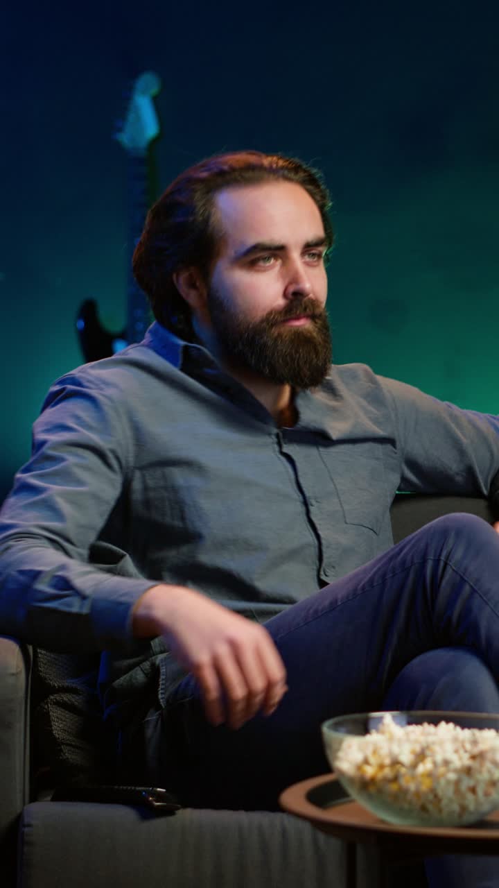 Vertical video Man at home watching interesting movie on TV