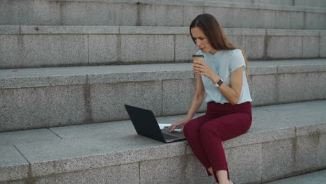 Geschäftsfrau-Arbeitet-Am-Laptop-In-Der-Stadt.-Manager-Trinkt-Kaffee-Zum-Mitnehmen-Auf-Der-Straße