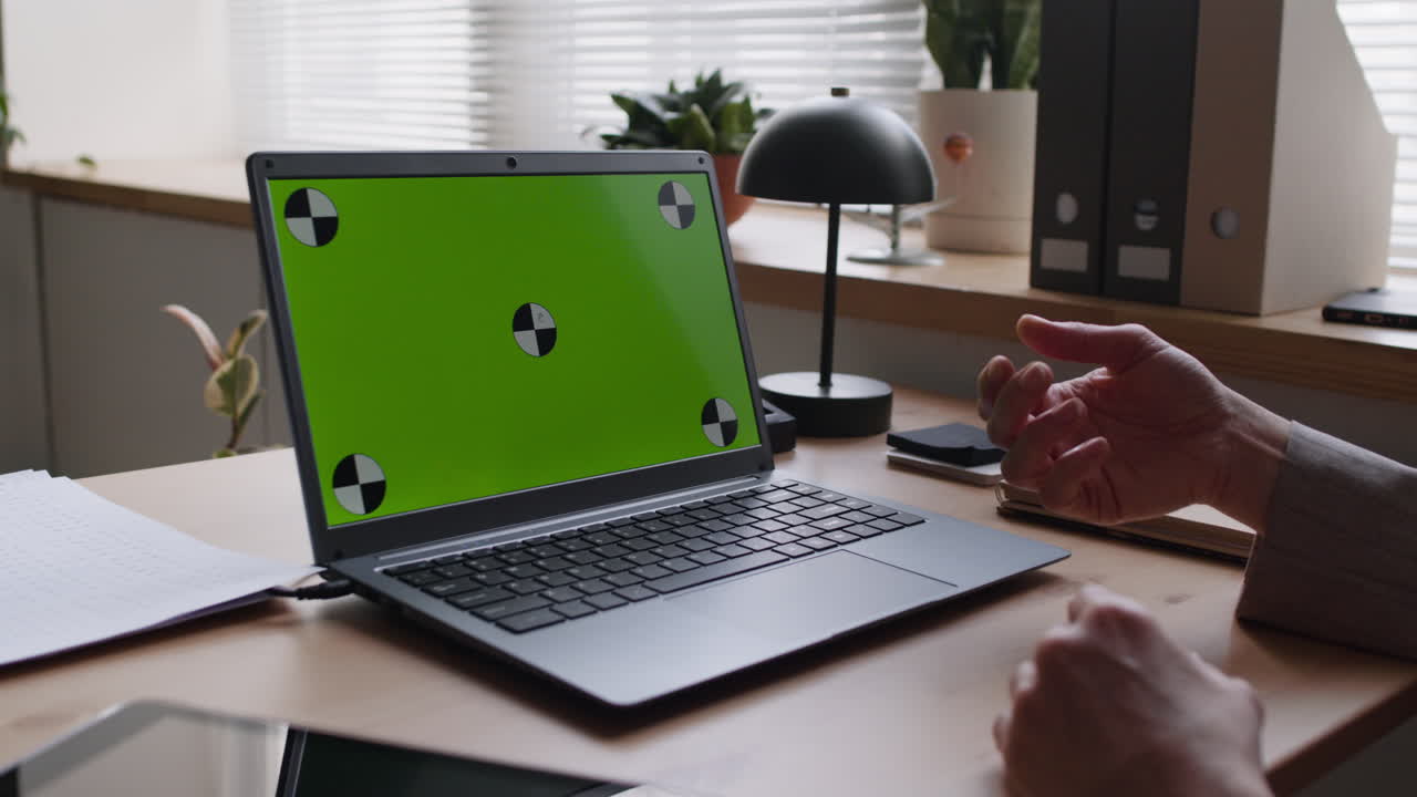 Person in a video conference with a green screen laptop