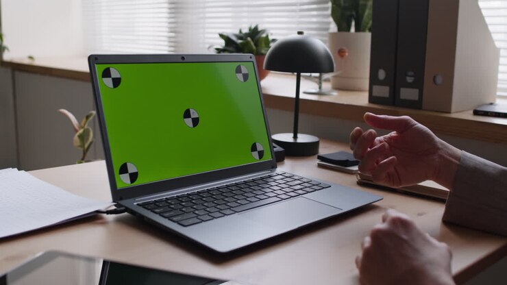 Personne en visioconférence devant un écran vert avec un ordinateur portable