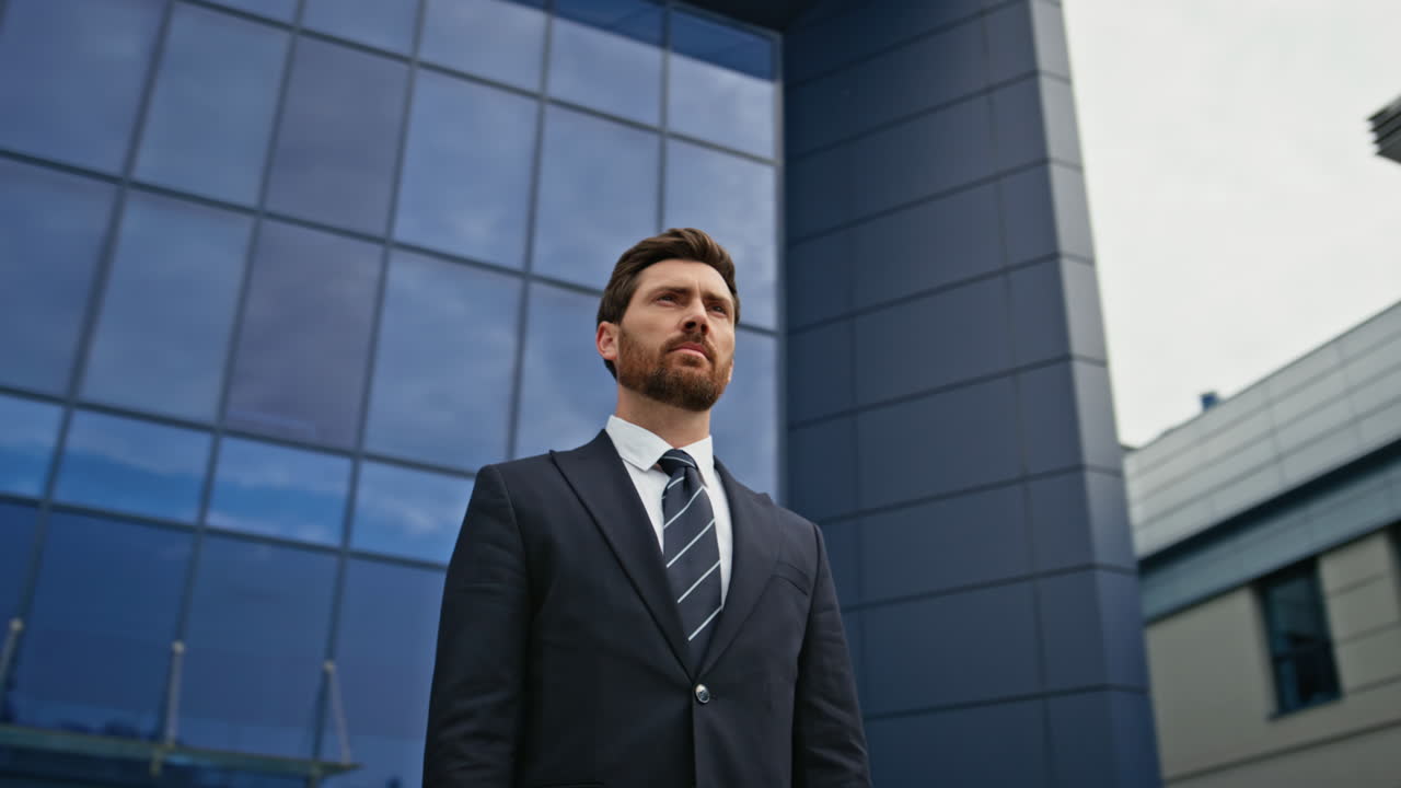 A businessman in a suit standing in front of a modern office building