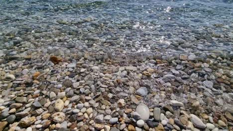 closeup of kinira beach, pebble beach, crystal clear water, waves splashing, thassos island, greece, europe