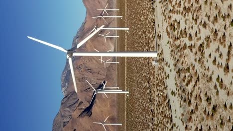 a wind turbine farm generating efficient renewable energy - ascending aerial view in vertical orientation