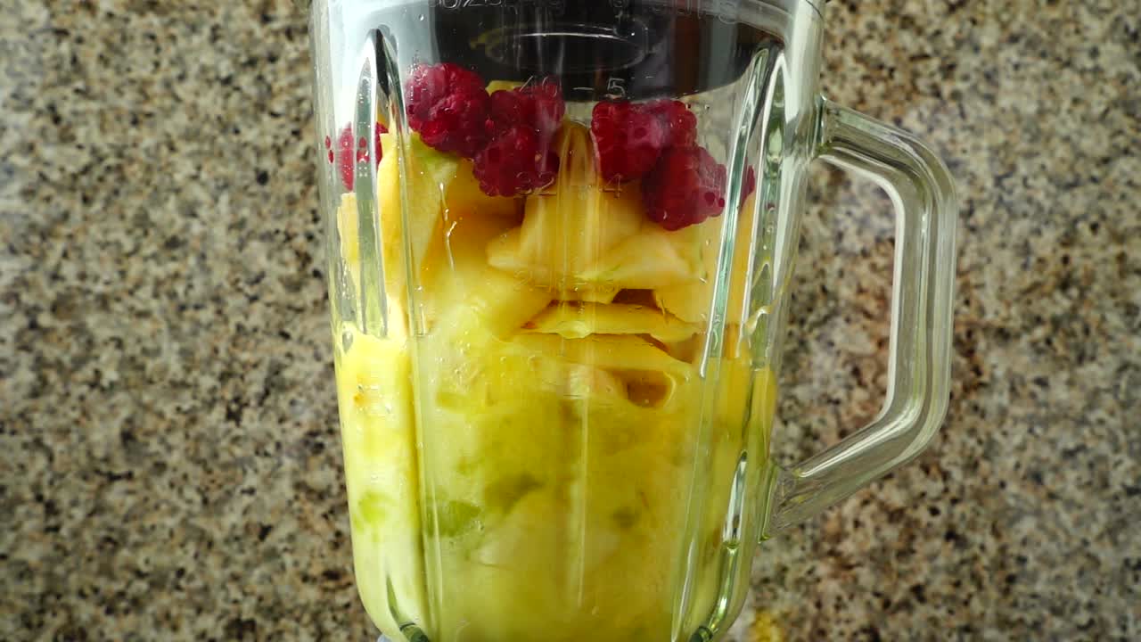 Cocktail med pærer, epler, druer, bringebær, bananer og appelsinjuice. Sakte film.