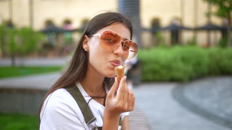 una mujer comiendo helado en un parque.